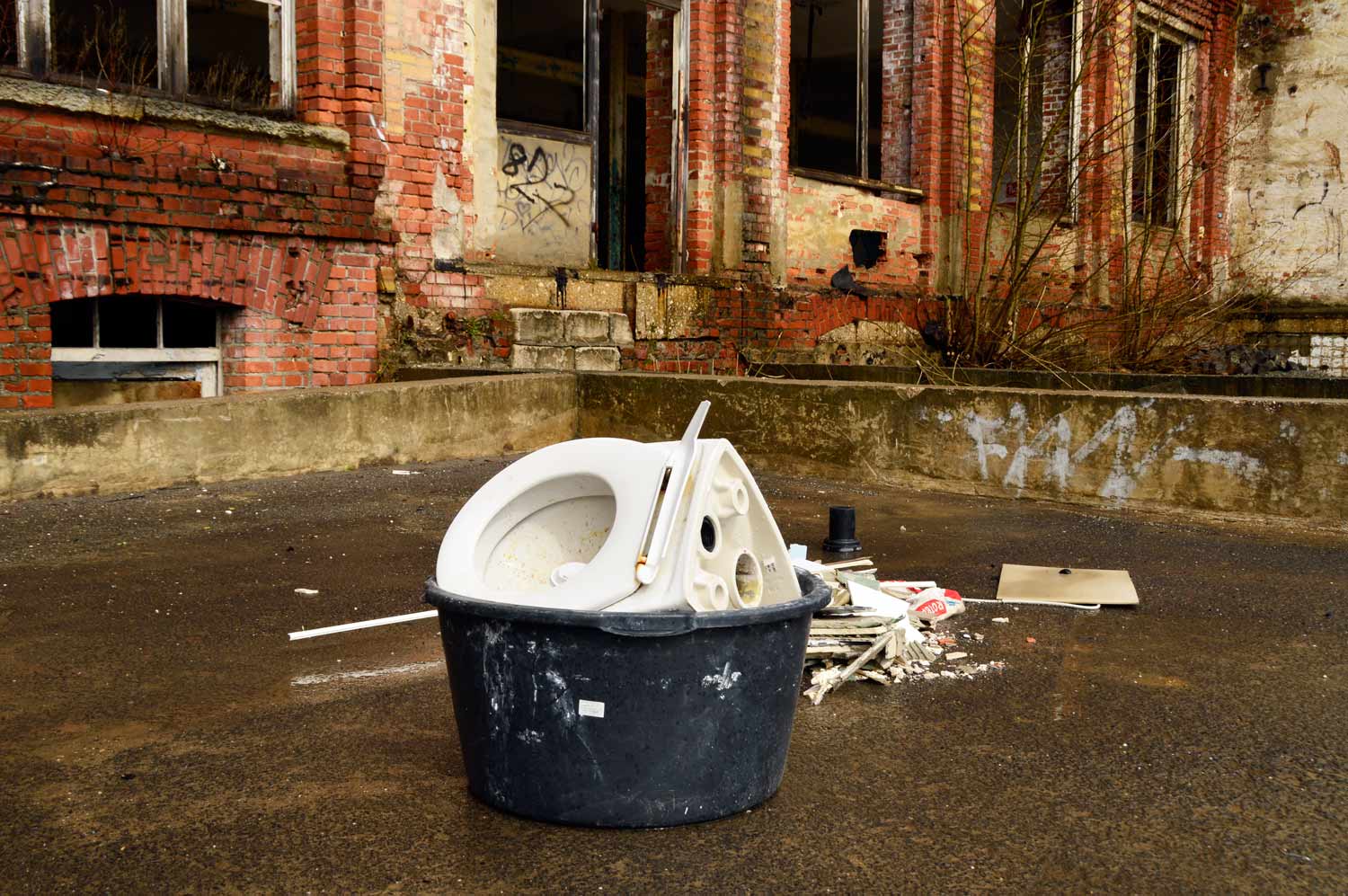 Eimer mit Toilettenbecken und Bauschutt Eimer mit Bauschutt