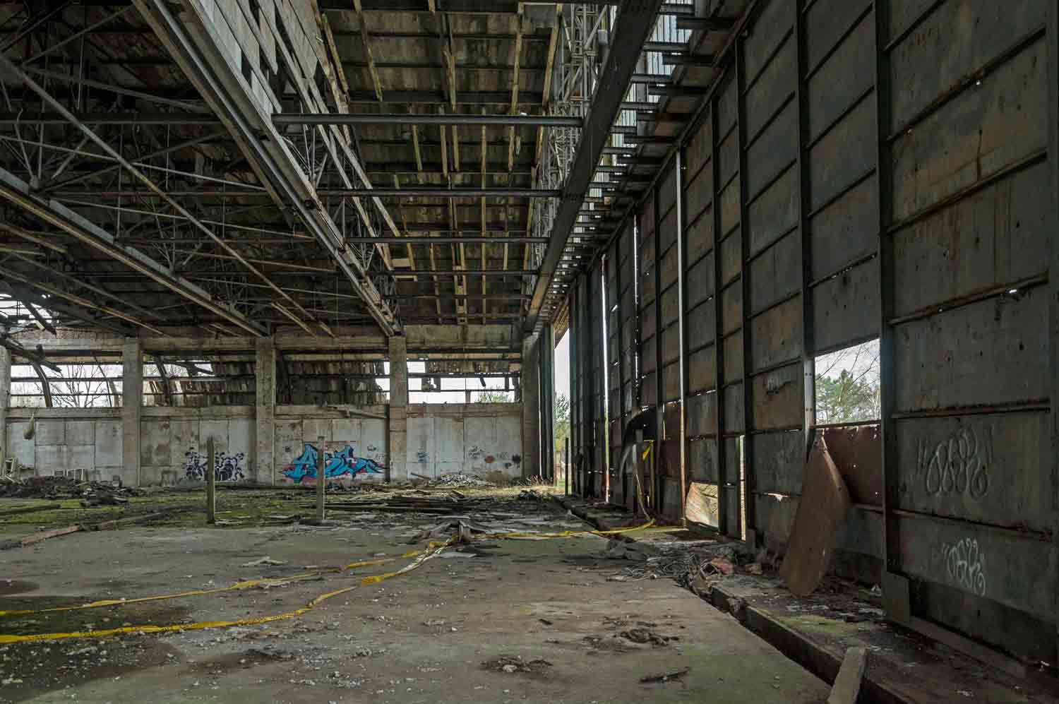 Inneres des Hangars mit marodem Dach, fehlenden Fenstern und undichten Toren