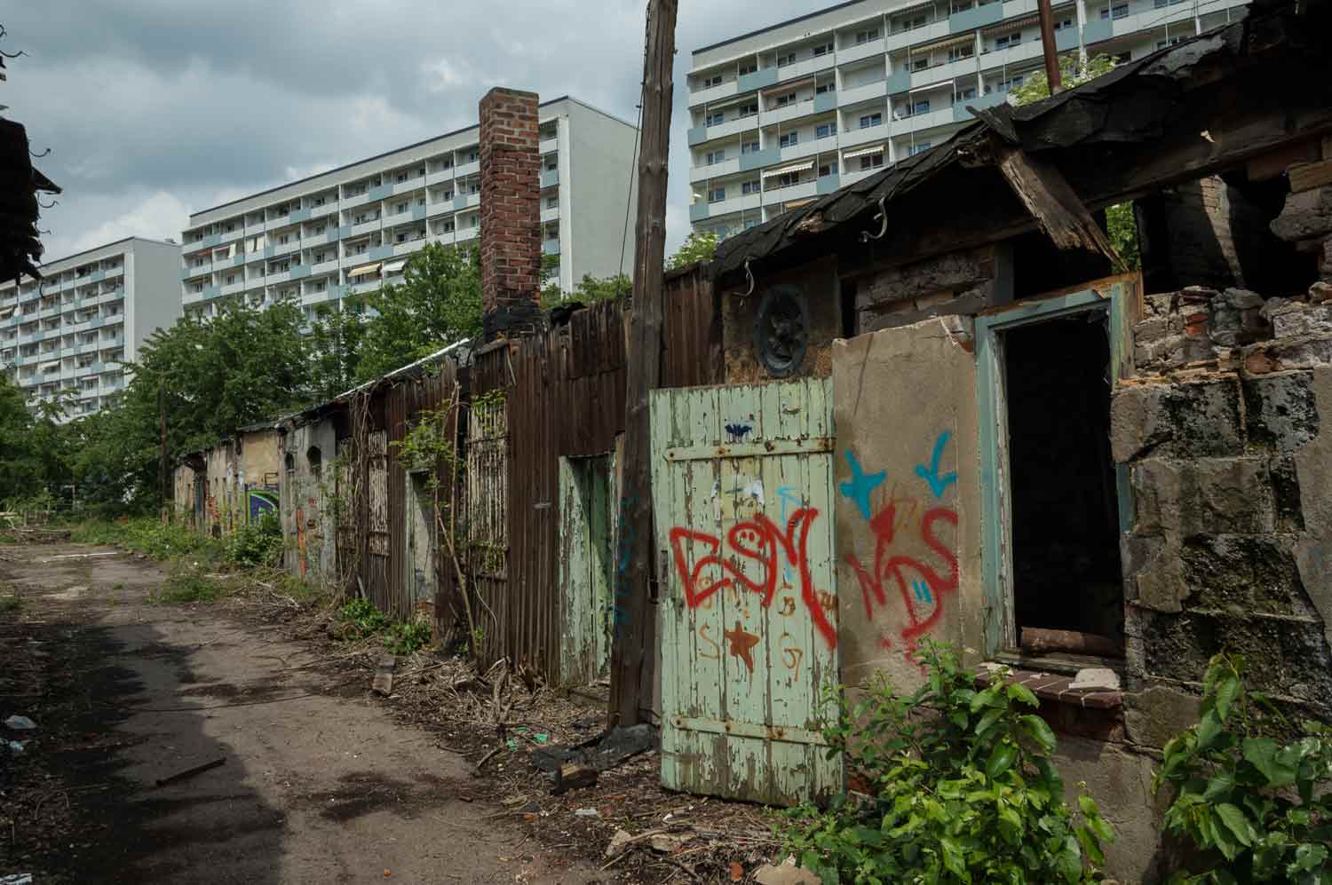 Verfallene Nebengebäude vor Neubaufront